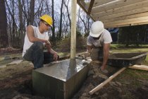 Hispanic carpenters using trowel to smooth concrete for staircase footing — Stock Photo