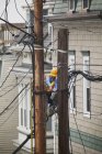 Cable lineman on ladder trimming wiring on city power poles — Stock Photo