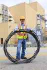 Ingenieur im Elektrizitätswerk trägt Drahtspule am Speicherplatz — Stockfoto