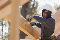 Carpenter measuring a laminated beam — Stock Photo