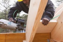 Carpenter with a nail gun on rafter braces — Stock Photo