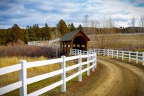 Covered bridge over a river in the countryside with dirt road; Oregon, United States of America — Stock Photo