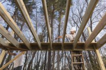 Carpinteiro hispânico instalando primeiro convés com cortes de canto em torno de postos de convés — Fotografia de Stock