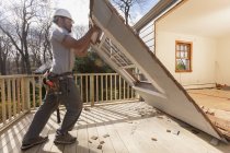 Hispanic carpenter removing newly cut door access to deck on home — Stock Photo