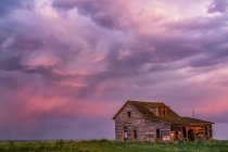 Celeiro abandonado em terras agrícolas com nuvens de tempestade brilhando rosa; Val Marie, Saskatchewan, Canadá — Fotografia de Stock