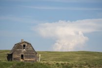 Grange abandonnée sur des terres agricoles avec formation de nuages unique au loin ; Val Marie, Saskatchewan, Canada — Photo de stock