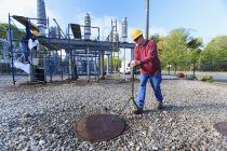 Power engineer accessing manhole cover at high voltage power distribution station — Stock Photo