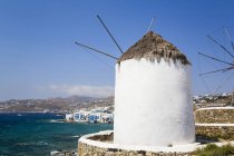 Mediterranean coastline of Greece with white buildings and windmills along the water edge; Greece — Stock Photo