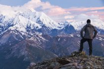 Visão traseira do homem no topo das montanhas cobertas de neve no Alaska Range; Alaska, Estados Unidos da América — Fotografia de Stock