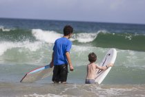 Dos hermanos surfeando en el océano - foto de stock
