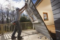 Carpinteiro hispânico removendo recém-cortado porta de acesso ao convés em casa — Fotografia de Stock
