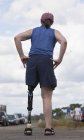 Mulher com perna protética em pé na estrada — Fotografia de Stock