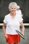 Портрет пожилой женщины, играющей в теннис и улыбающейся — стоковое фото