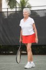 Старша жінка грає в теніс і посміхається — стокове фото