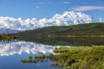 Denali showing well with the blue waters of Wonder Lake, Denali National Park and Preserve; Alaska, United States of America — Stock Photo