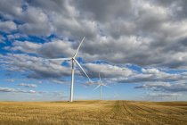 Éoliennes sur un vaste champ de terres agricoles sous un ciel nuageux ; Saskatchewan, Canada — Photo de stock