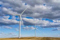Turbinas eólicas em um vasto campo de terras agrícolas sob um céu nublado; Saskatchewan, Canadá — Fotografia de Stock