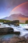 Double rainbow shining over a rugged waterfall and the Rocky Mountains, Jasper National Park; Alberta, Canada - foto de stock