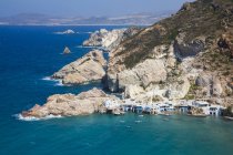 Fyropotamos Village with boats in the small harbour and a view of the rugged coastline; Fyropatamos, Milos Island, Cyclades, Greece — стоковое фото