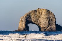 Un bateau de pêche est encadré par une arche en pierre à Rockaway Beach ; Rockaway, Oregon, États-Unis d'Amérique — Photo de stock