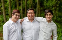 Un retrato de un padre con dos hijos, todos con camisas blancas; Langley, Columbia Británica, Canadá - foto de stock
