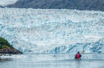 Kayaker frente a un glaciar de marea en Prince William Sound; Alaska, Estados Unidos de América - foto de stock