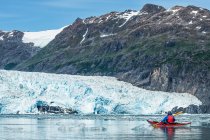 Kayaker remando frente a un glaciar de marea en Prince William Sound; Alaska, Estados Unidos de América - foto de stock