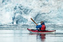 Kayaker frente a un glaciar de marea en Prince William Sound; Alaska, Estados Unidos de América - foto de stock