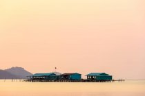 Erhöhte Gebäude auf dem Wasser während eines leuchtend rosa Sonnenuntergangs, Seestern-Strand; Phu Quoc, Provinz Kien Giang, Vietnam — Stockfoto