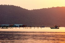 Barcos y edificios en el agua durante una puesta de sol rosa brillante, playa Starfish; Phu Quoc, provincia de Kien Giang, Vietnam - foto de stock