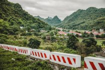 Barriere attraverso il paesaggio con una città e fogliame lussureggiante che copre le formazioni calcaree carsiche; Cat Ba Island, Vietnam — Foto stock
