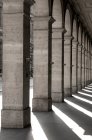 Square columns in a row with shadows cast on the ground; Paris, France — Stock Photo