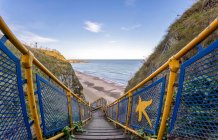 Escaleras con barandilla colorida que conduce a la playa, Marsden Bay; South Shields, Tyne and Wear, Inglaterra - foto de stock
