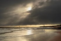 Silhouetted lighthouses along the coastline under dramatic cloudy sky; Whitburn Village, Tyne and Wear, England — Stock Photo