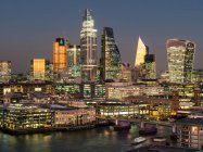 Cityscape and skyline of London at dusk with 20 Fenchurch, 22 Bishopsgate, and various other skyscrapers, and the River Thames on the foreground; London, England — стокове фото