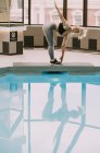 Frau trainiert auf einer Matte neben einem Pool; Wellington, Neuseeland — Stockfoto