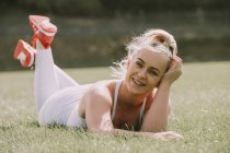 Young woman lying on a grass field in her workout wear; Wellington, New Zealand — Stock Photo