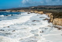 Strandschaum, der durch Wellen entsteht, die auf einen Strand im Wilder Ranch State Park (Kalifornien, Vereinigte Staaten von Amerika) stürzen — Stockfoto