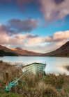 A boat on a lake shoreline with a valley and mountains in the background; Black Valley, County Kerry, Ireland — Stock Photo
