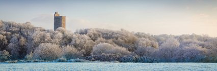 Килвортский замок, старый замок руины с видом на заснеженный лес и поле зимой на восходе солнца, сшитые композитные панорамы; Килворт, графство Корк, Ирландия — стоковое фото