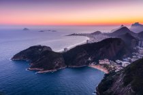 Pôr-do-sol brilhante sobre o oceano Atlântico e a costa de colinas e praias do Rio de Janeiro; Rio de Janeiro, Rio de Janeiro, Brasil — Fotografia de Stock