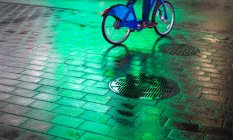 Bicicleta ciclista na passarela molhada com luz verde brilhante à noite em Manhattan; Nova York, Nova York, Estados Unidos da América — Fotografia de Stock