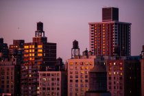 Edifícios residenciais no crepúsculo com unidade HVAC e reservatórios de água nos telhados; Nova York, Nova York, Estados Unidos da América — Fotografia de Stock