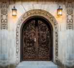 Ornate Doppeltüren mit dekorativen Schnitzereien an den Wänden und angebrachten beleuchteten Wandleuchten; New York City, New York, Vereinigte Staaten von Amerika — Stockfoto