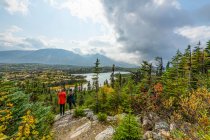 Two women standing on a rock overlooking the landscape of Wright Pass near the Canada \ USA border; Yukon, Canada — Stock Photo