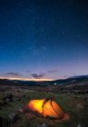 Une tente éclairée dressée dans les montagnes Wicklow la nuit avec des étoiles dans le ciel ; Comté de Wicklow, Irlande — Photo de stock