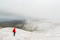 Escursionista donna in giacca rossa escursioni su una montagna innevata in inverno in caso di maltempo, Galty Mountains; Contea di Tipperary, Irlanda — Foto stock