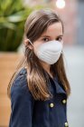 Jeune fille debout portant un masque de protection contre la COVID-19 pendant la pandémie mondiale de coronavirus ; Toronto, Ontario, Canada — Photo de stock