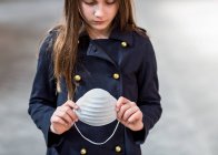 Jeune fille tenant un masque de protection dans ses mains pendant la pandémie mondiale de coronavirus ; Toronto, Ontario, Canada — Photo de stock