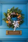 A decorative Christmas wreath on a blue house door; London, England — Stock Photo